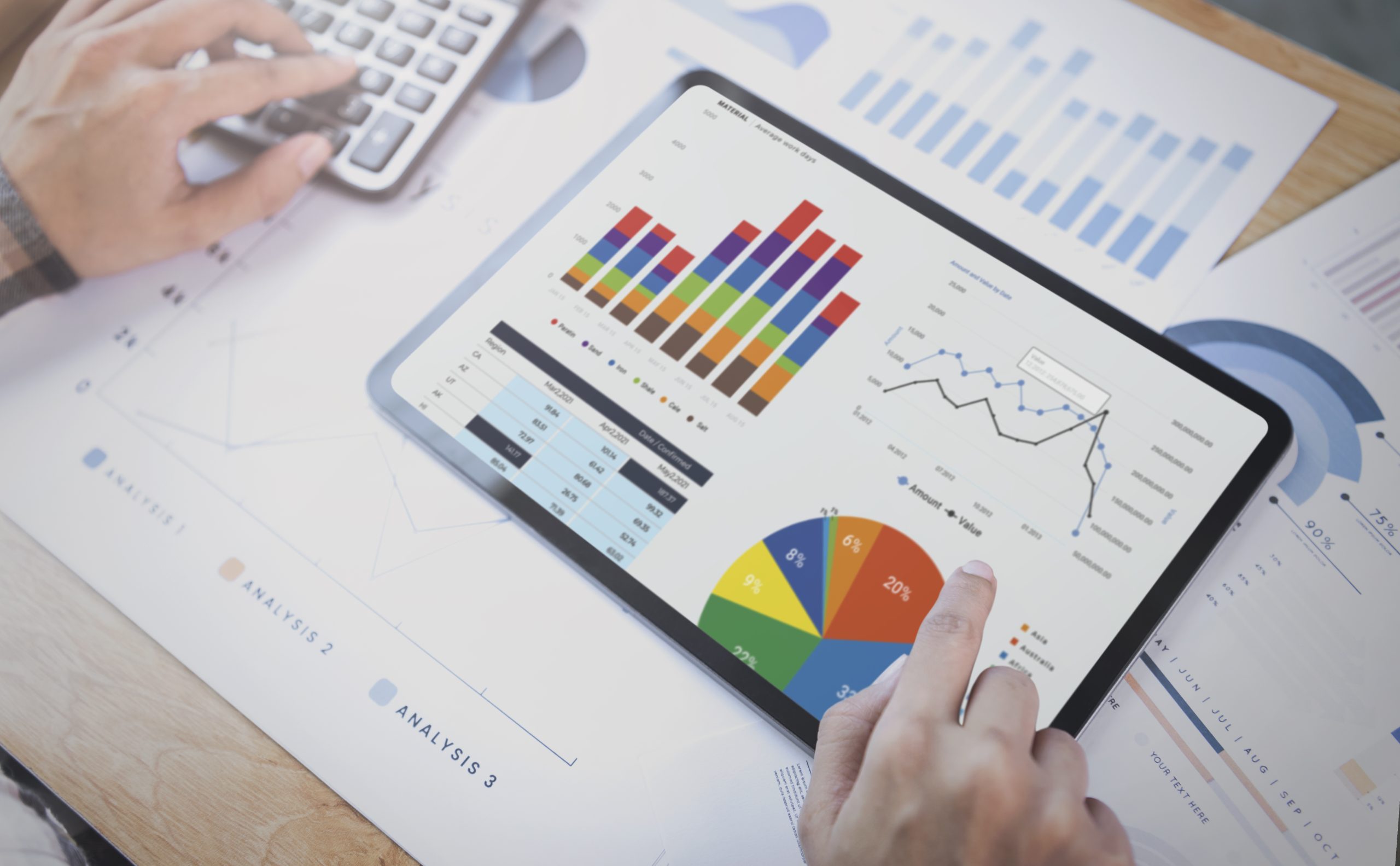Tablet displaying graphs and charts used for analyzing and planning a digital marketing strategy, with additional financial documents and data on the desk.