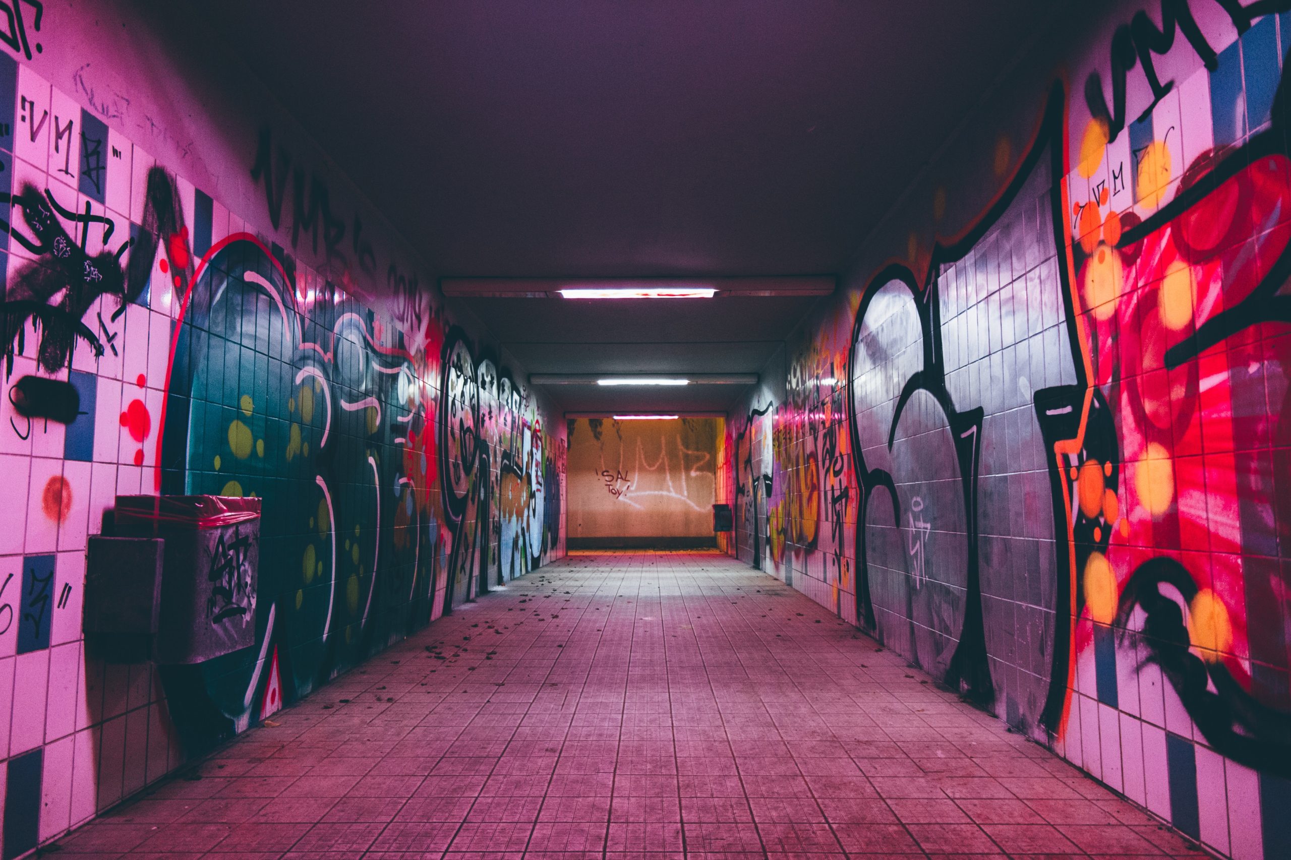 A neon-lit underpass decorated with bright street art