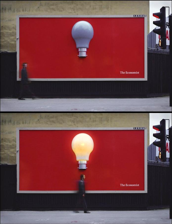 Innovative billboard advertising by The Economist featuring a red background with a light bulb that illuminates when a person walks underneath, symbolizing bright ideas and intelligence.