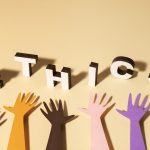 Colorful hands reaching up towards 3D letters spelling 'ETHICS,' symbolizing the importance of ethical marketing practices and inclusive business values.