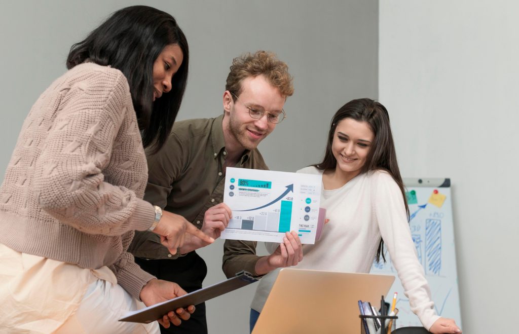 Group of professionals discussing a successful digital marketing campaign while reviewing performance metrics and charts in a collaborative workspace.