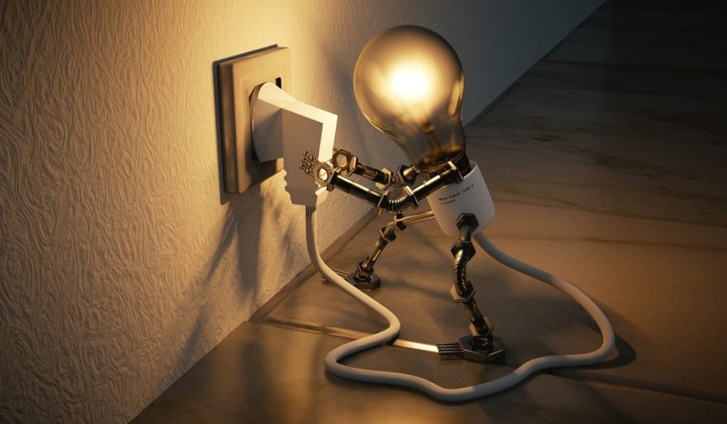A creative depiction of a light bulb with legs plugging itself into a power socket, symbolizing innovation and ideas powering creative marketing strategies.