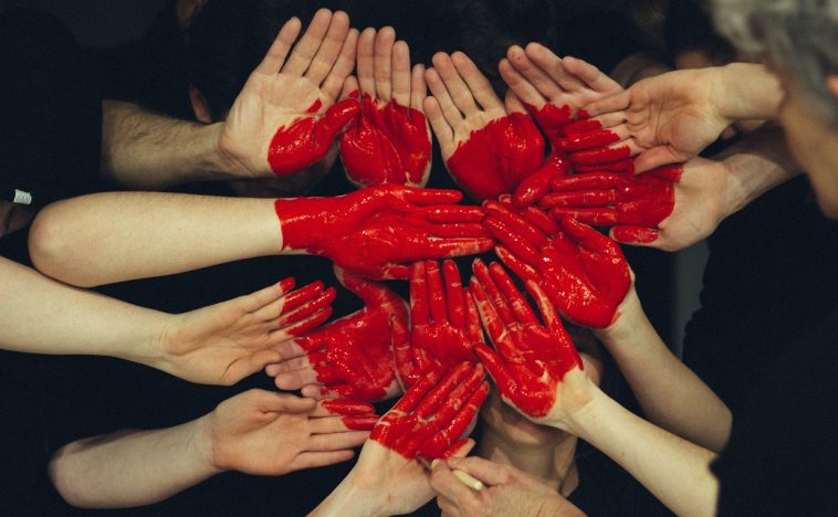 Group of hands painted red forming a heart shape, symbolizing collaboration and the essence of customer-centric marketing focused on building meaningful connections.