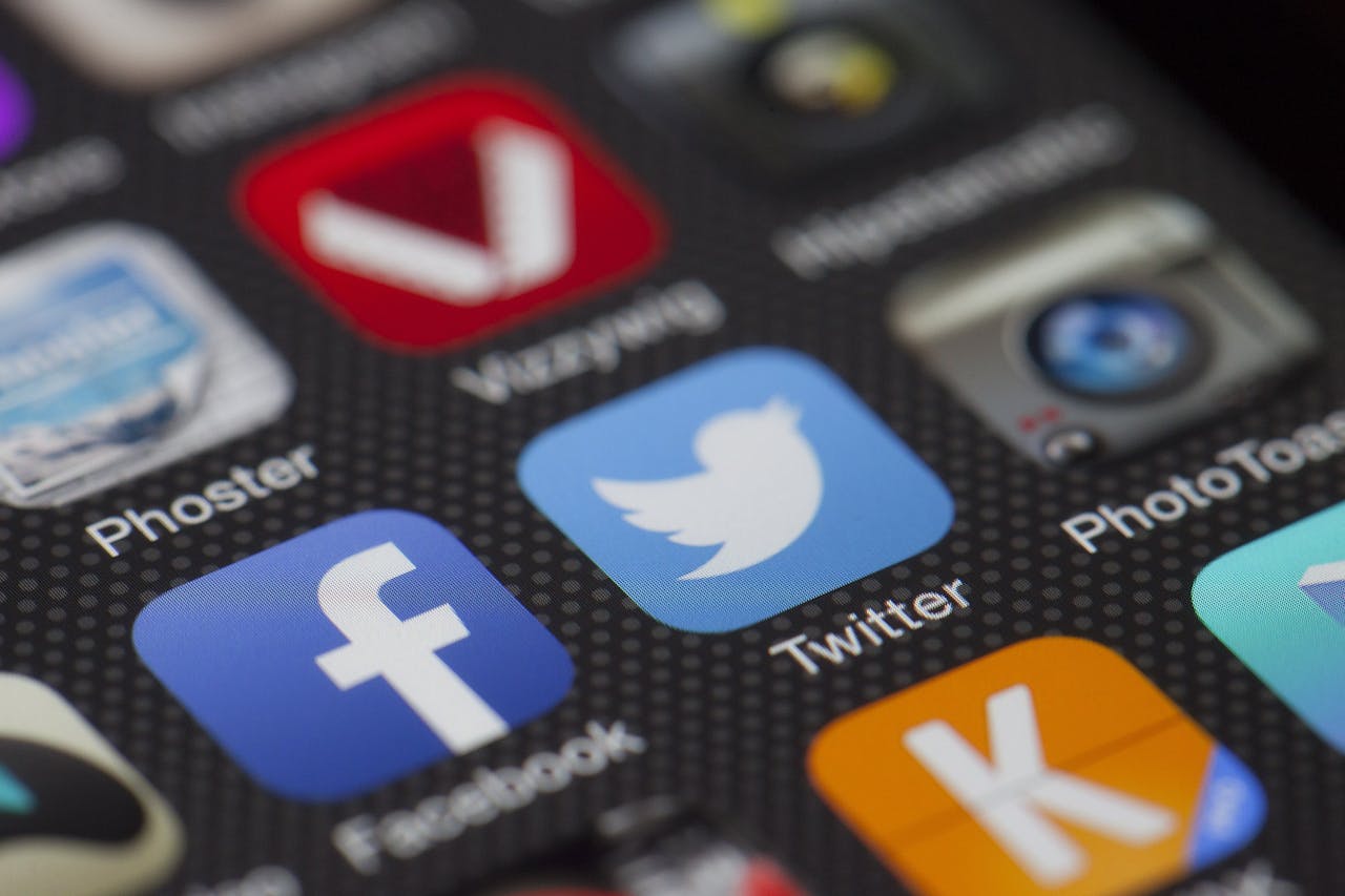 Close-up of a smartphone screen displaying various social media app icons, including Facebook and Twitter, illustrating the importance of social media platforms in content marketing.